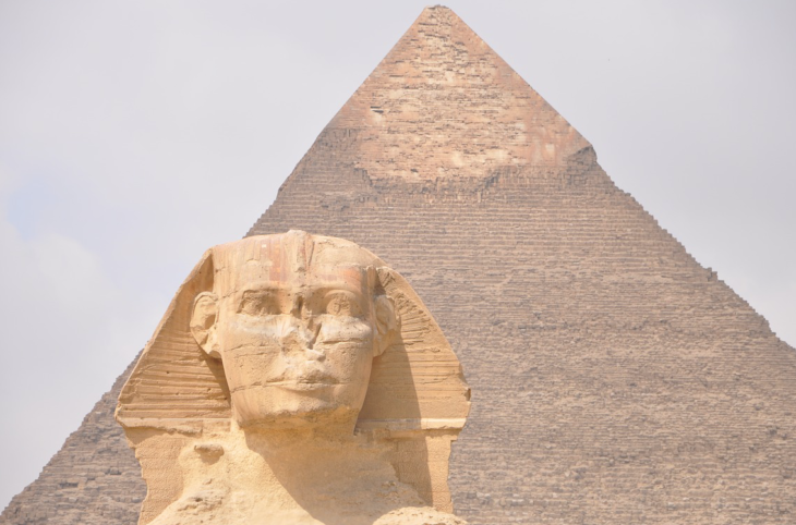 a statue of a man in front of a pyramid
