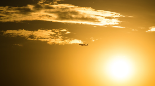 an airplane flying in the sky with the sun