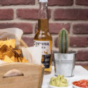 a bowl of chips and a cactus next to a bottle of beer