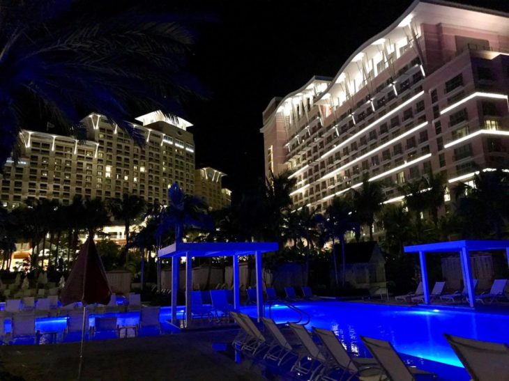 a pool with blue lights in front of a large building