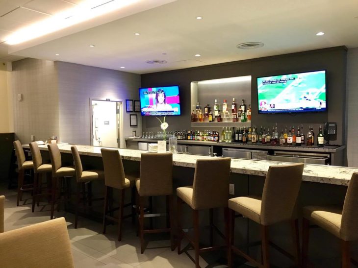 a bar with a row of chairs and televisions