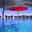 a pool with a red umbrella and chairs