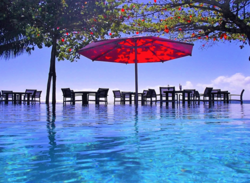 a pool with a red umbrella and chairs