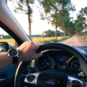 a hand on a steering wheel of a car