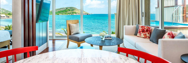 a room with a table and chairs by the ocean