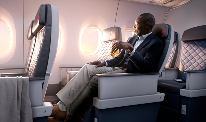 a man sitting in an airplane with a drink
