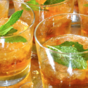 a group of glasses with ice and mint leaves