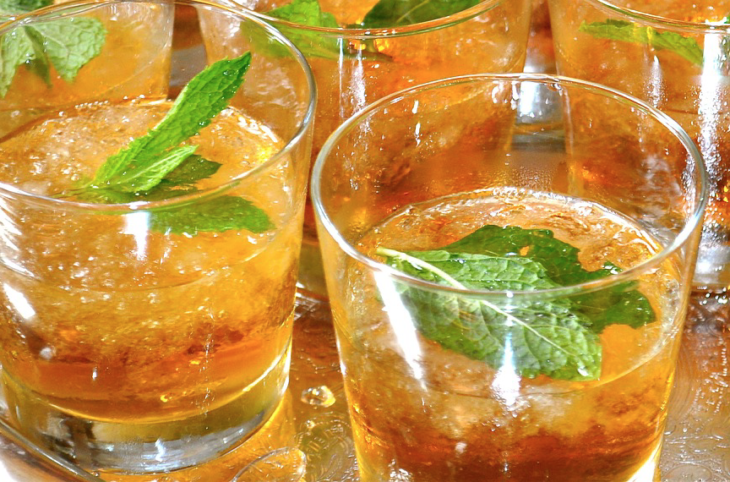 a group of glasses with ice and mint leaves