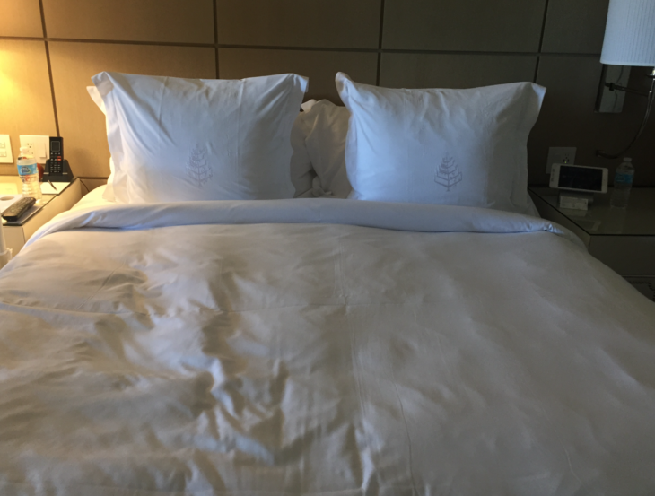 a bed with white pillows and a lamp