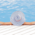 a person wearing a hat sitting by a pool