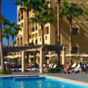 a pool with palm trees and people sitting on it