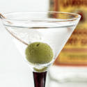 a martini glass with a green olive in it