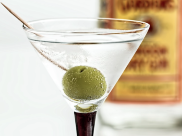 a martini glass with a green olive in it