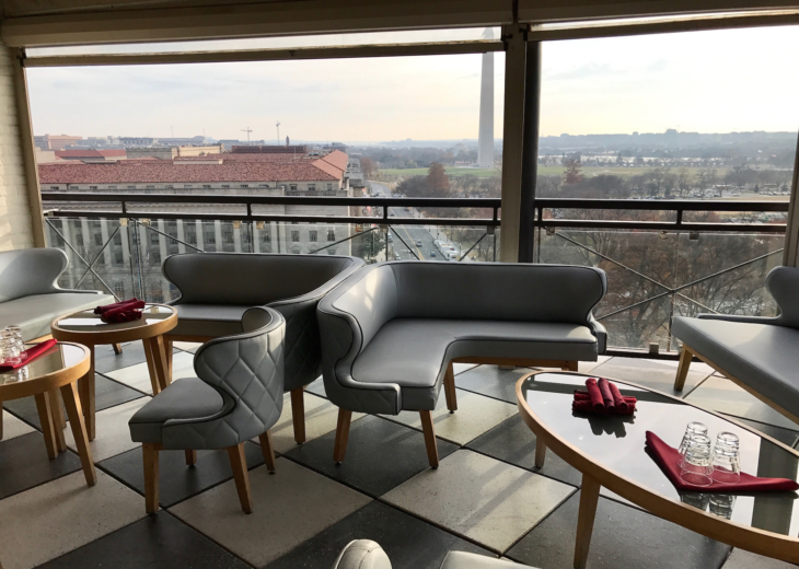 a couches and tables in a room with a view of a city