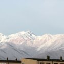a group of buildings with snow covered mountains in the background