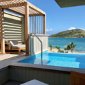 a pool with a wooden structure and a beach in the background