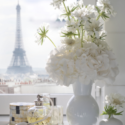 a white vase with flowers and perfume bottles