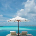 a deck chair and umbrella by a pool