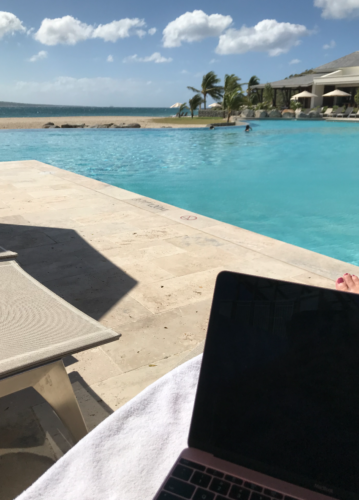 a laptop on a towel next to a pool