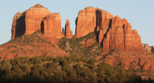 a red rock formations with trees with Cathedral Rock in the background