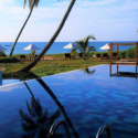 a pool with a view of the ocean and palm trees