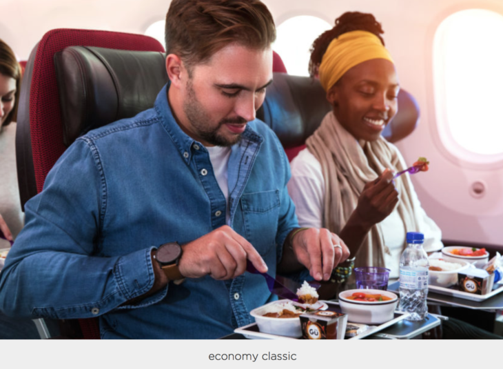 a man and woman eating food on an airplane