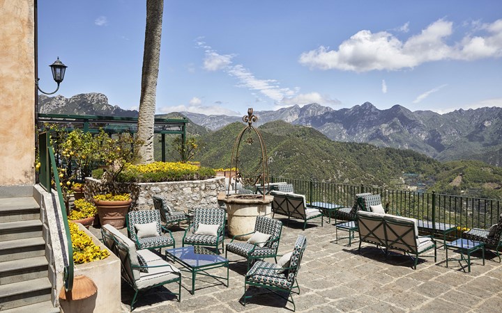 a patio with chairs and a fountain on a hill