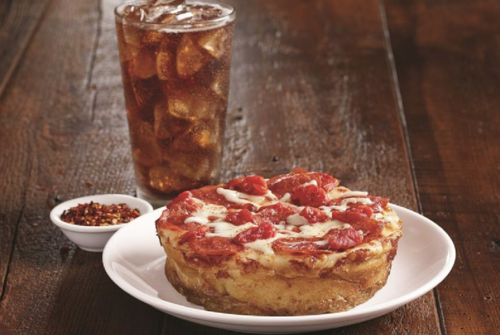 a pizza on a plate next to a glass of ice