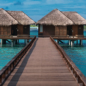 a wooden walkway leading to a hut on water