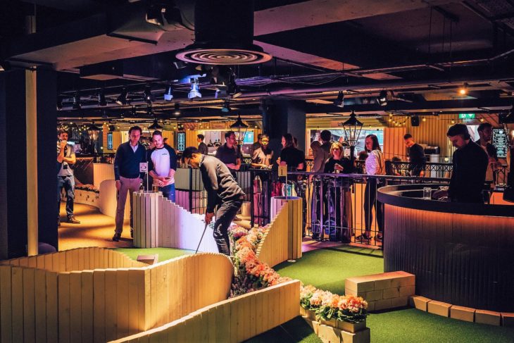a group of people in a room with a miniature golf course