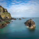 a rocky shore with a cliff in the background