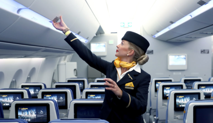 a woman in uniform and hat touching an overhead panel