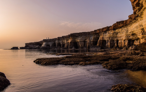 a rocky cliff with water in the background