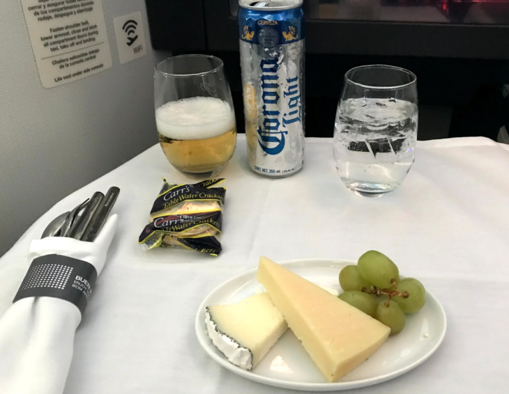 a plate of cheese grapes and a can of beer on a table