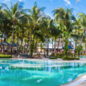 a pool with palm trees and a building