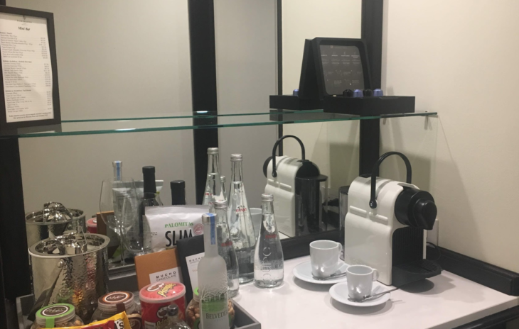 a counter with a glass shelf and a coffee maker and other items