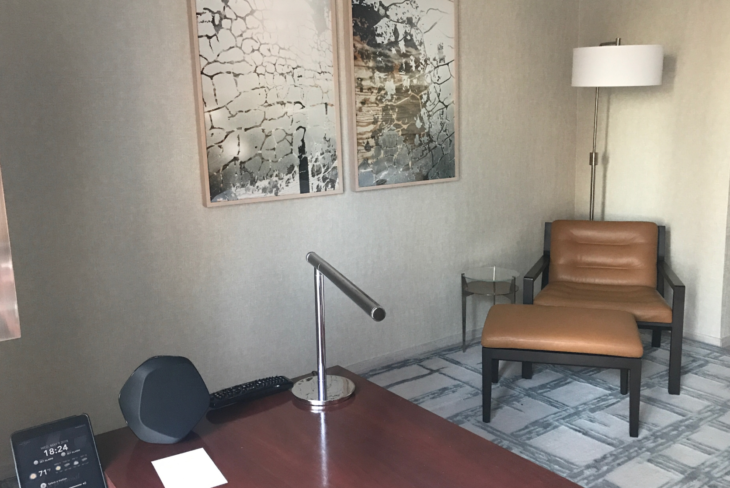 a desk with a microphone and a chair in a room with art on the wall
