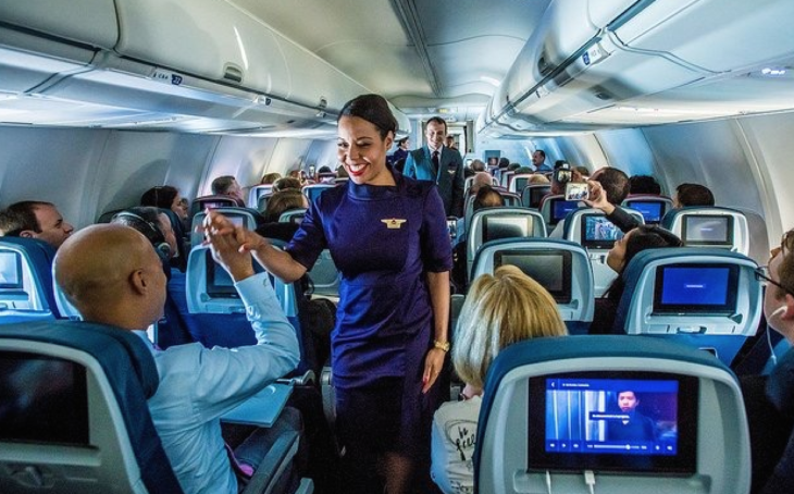 a woman in a purple dress standing in an airplane
