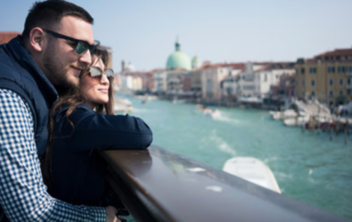 a man and woman leaning on a railing looking at a river