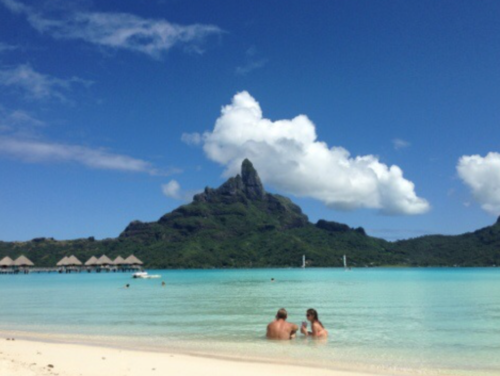 people in the water with a mountain in the background