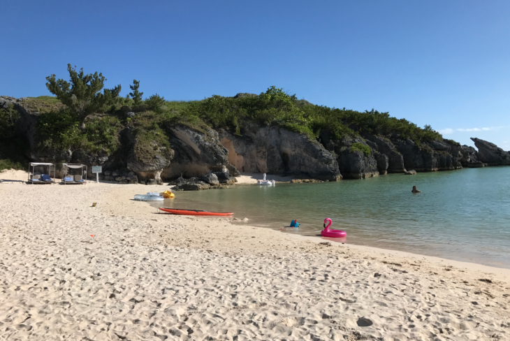 a beach with a body of water and a rock cliff