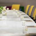 a long table with glasses of water and yellow chairs