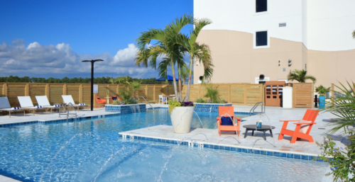 a pool with a palm tree and chairs