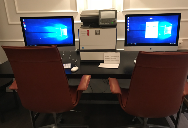 a desk with computers and a printer