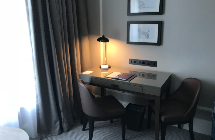 a desk with a lamp and picture frames on the wall