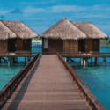 a wooden walkway leading to a hut on water