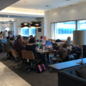 a group of people sitting at tables in a room with windows