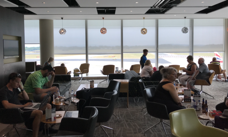 people sitting at tables in a room with large windows