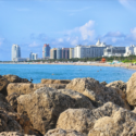 a rocky beach with buildings in the background
