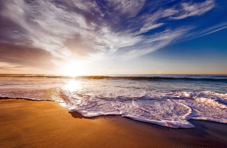 a beach with waves and a blue sky